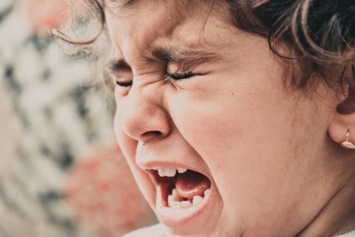 A young child crying with eyes squeezed shut and mouth wide open