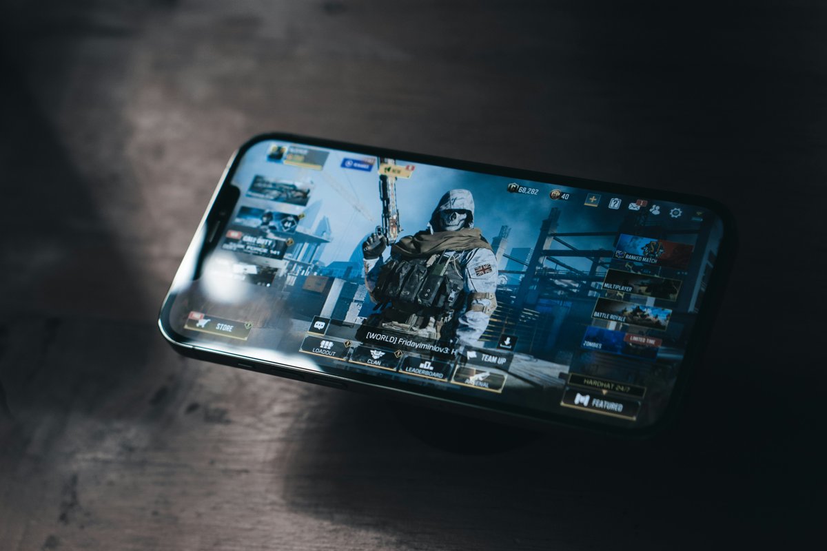 A phone lying on a dark wooden table showing a mobile video game menu